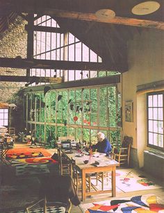 an old man sitting at a table in front of a large window with lots of windows