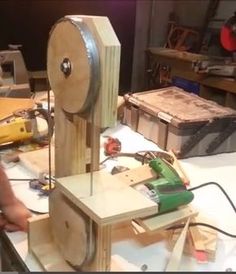 a person is working on a project with wood and wires attached to it, while another man holds a cordless device in front of him