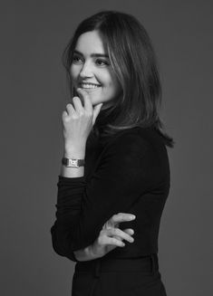 a black and white photo of a woman with her hand on her chin smiling at the camera