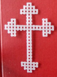 the cross is made out of paper and placed on a red surface with white squares