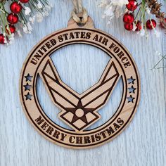 an air force christmas ornament hanging on a wooden background with red berries and greenery