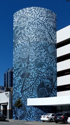 a tall building with blue and white designs on it's side in front of a parking lot