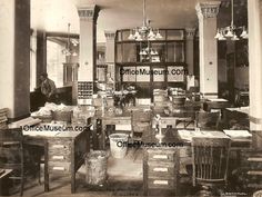 an old black and white photo of a room with desks, chairs, and other items