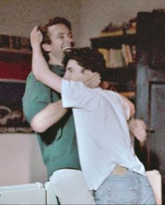 two men hugging each other in the living room