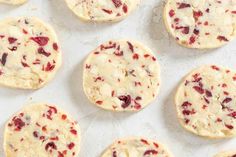 several cookies with cranberry toppings are arranged on a baking sheet and ready to be baked