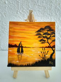 an easel with a painting on it that has a sailboat in the water