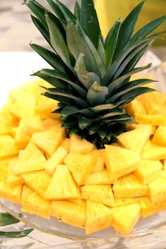 a pineapple is piled on top of another pineapple in a glass bowl with leaves