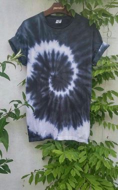 a black and white tie - dye shirt hanging on a wall next to a plant