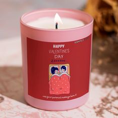 a pink candle is sitting on a table with a red cover and the words happy valentine's day printed on it