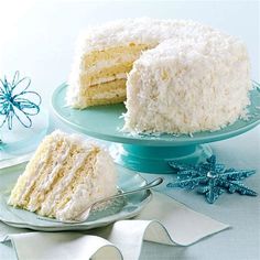 a white cake with coconut frosting on a plate next to a slice cut from it