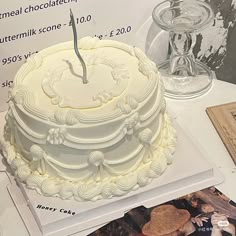 a white cake sitting on top of a table next to a magazine and glass vase