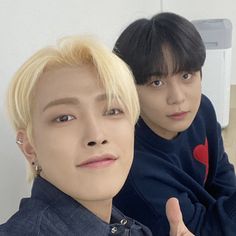 two young men sitting next to each other in front of a mirror with one giving the thumbs up