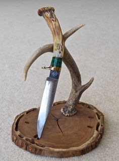 a knife with antlers on it sitting on top of a piece of wood