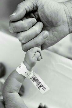 a black and white photo of an adult holding a baby's hand