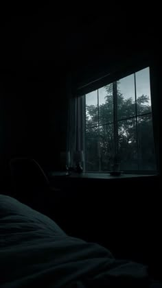 a dark room with a bed and window