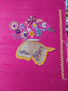 a close up of a pink cloth with flowers and a butterfly embroidered on the side