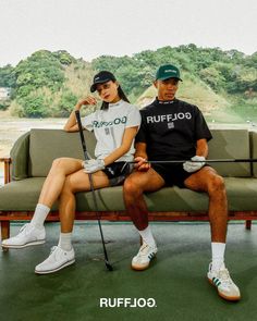 a man and woman are sitting on a couch with golf clubs in their hands,