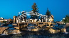 the entrance sign to idaho falls is lit up at night with waterfall cascading