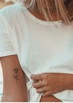 a woman with a flower tattoo on her left arm and right arm behind her back