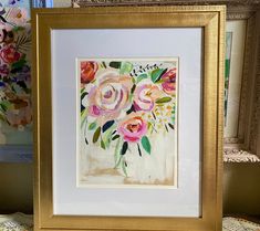 there is a painting with flowers in it on the table next to other pictures and frames