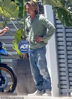 a man standing next to a potted plant in front of a building