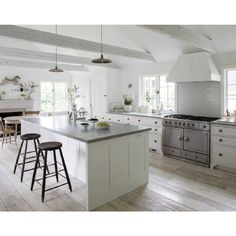 a large kitchen with white cabinets and an island in front of the stove top oven