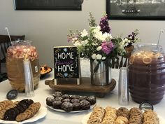 a table topped with cookies and pastries next to vases filled with purple flowers