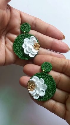 a pair of green and white crochet earrings with flowers on each earring