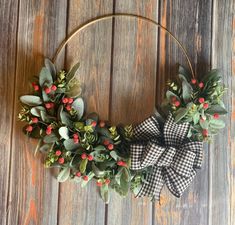 a wreath with red berries and greenery is hanging on a wooden wall in front of a door