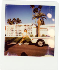 a polaroid photograph of a woman in front of a white truck and palm trees