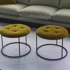 two round stools sitting next to each other on a white floor in front of a couch