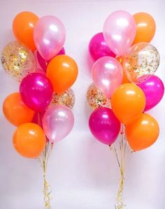 two bunches of balloons with gold and pink confetti on them against a white wall