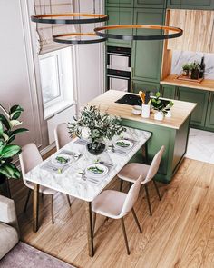 a kitchen with green cabinetry and marble dining table surrounded by white chairs in the center