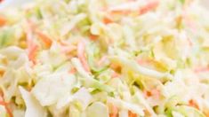 a salad with carrots, cabbage and lettuce in a white bowl on a table