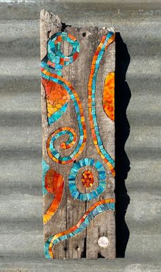 a piece of wood that has been painted with orange and blue designs on the side