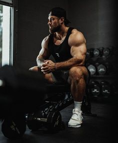 a man sitting on top of a bench in a gym