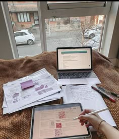 a person sitting at a table with an open laptop and papers on top of it