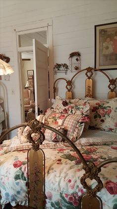 a bed with floral bedspread and pillows in a white room next to an open door