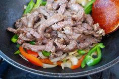 a skillet filled with meat and vegetables on top of a stove next to an orange peel