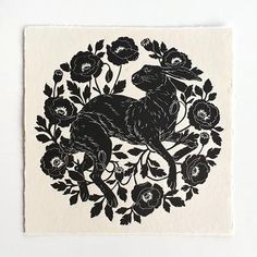 a black and white drawing of a rabbit surrounded by flowers on a piece of paper