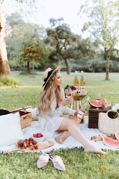 a woman is sitting on the grass with her picnic