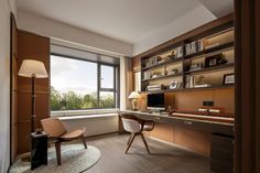 a room with a desk, chair, and bookcases in front of a large window