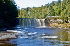 a large waterfall with water coming out of it's sides and trees in the background