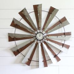 a metal clock mounted to the side of a white wall next to a wooden floor