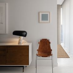 a chair sitting in front of a white wall next to a wooden cabinet and window