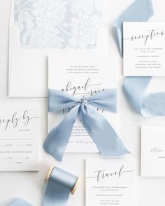 the wedding stationery is laid out on top of each other and tied together with blue ribbon