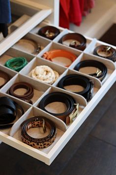 an open drawer with many different belts in it