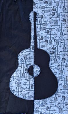 an acoustic guitar is laying on top of a quilted piece of fabric with black and white designs