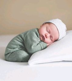 a newborn baby sleeping on top of a white pillow with a knitted headband