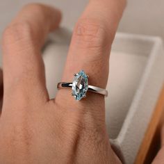 a woman's hand with a ring on it and a blue topaz stone